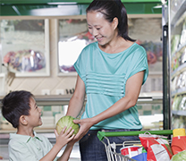 A mother hands her child some produce.